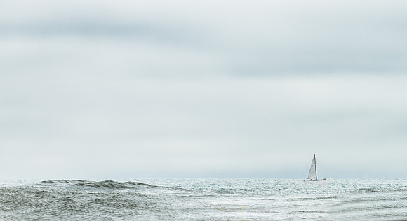 Solitary Sailboat on the gently rolling pacific ocean.