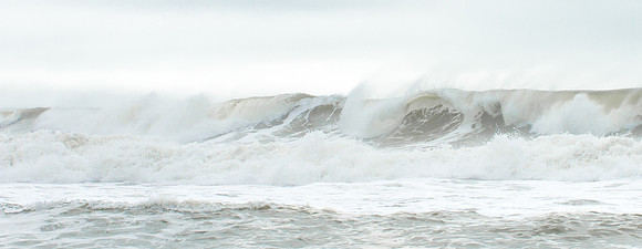 Wind blows spray off of powerful waves.